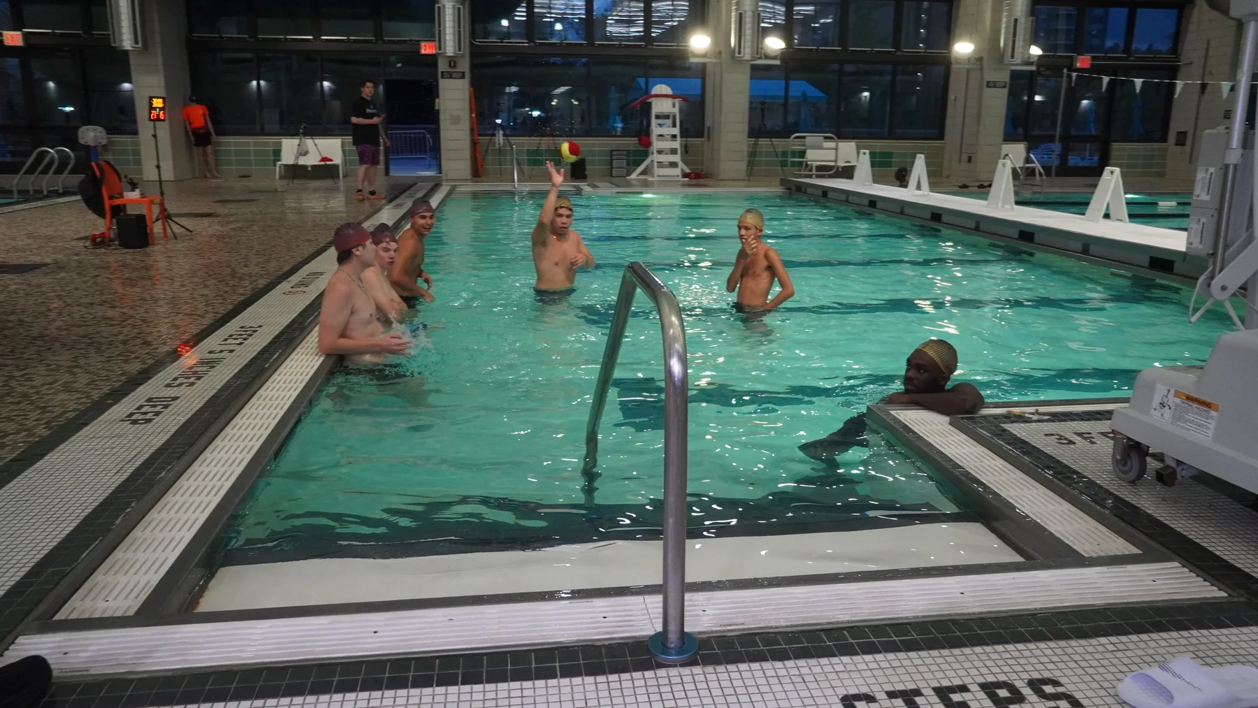 A group of players in the pool, with one tossing the ball into the air.